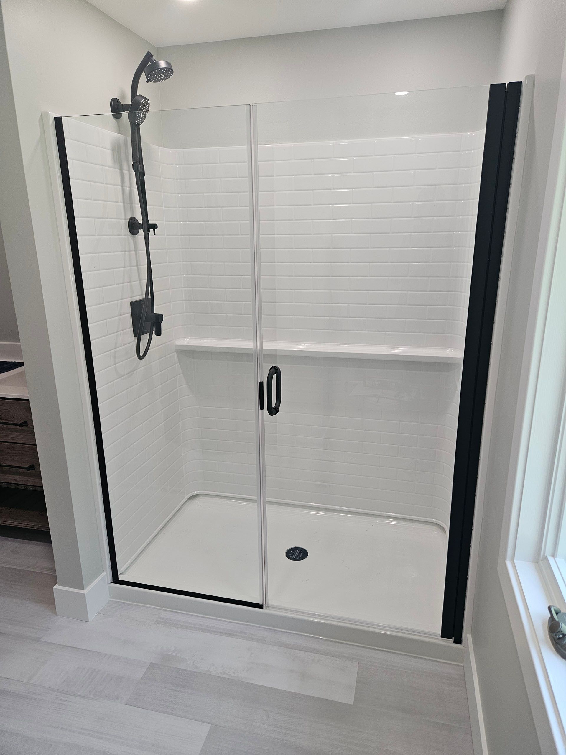 Door and panel - A bathroom with a walk-in shower with a glass door.