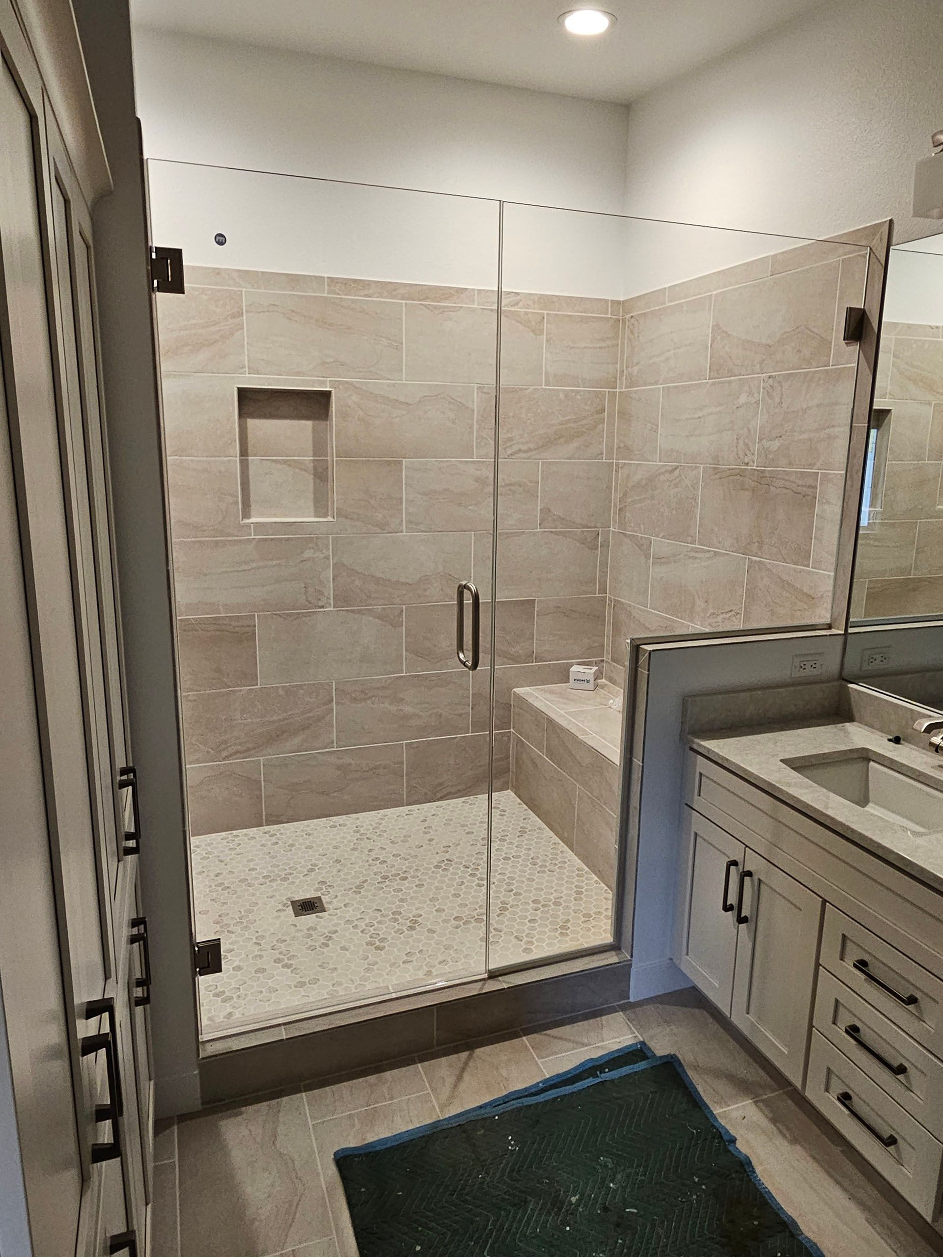 Door and panel - A bathroom with a walk-in shower with a glass door.