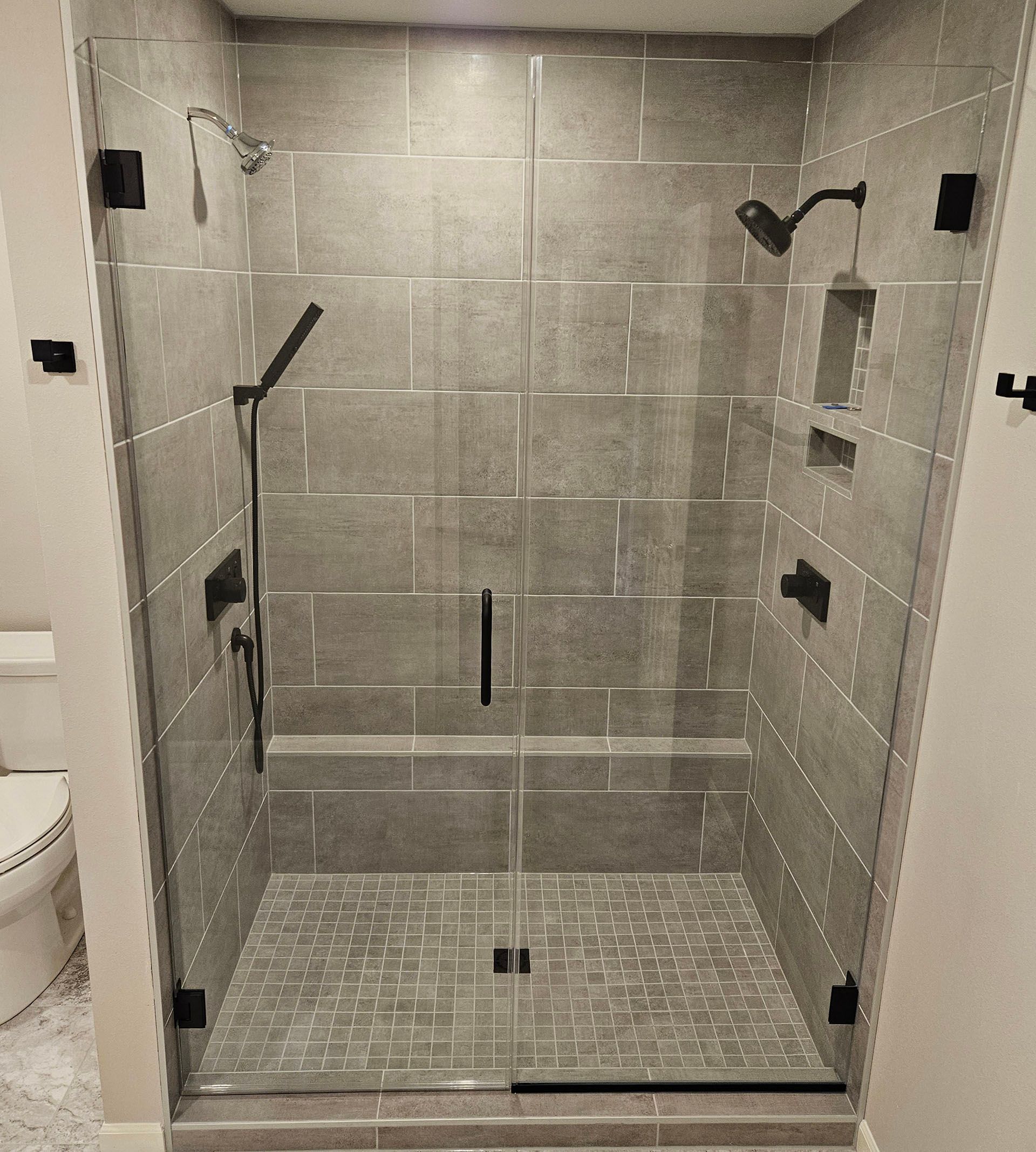 Door and panel - A bathroom with a walk-in shower with a glass door.