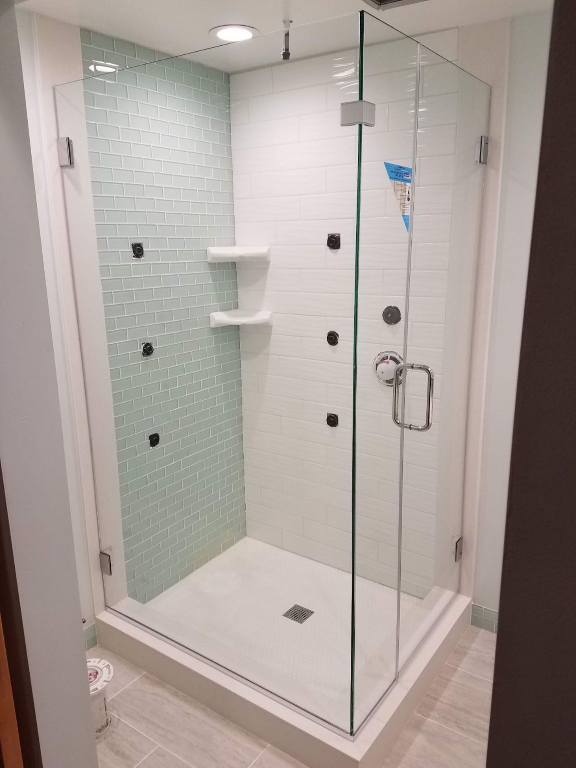 Return panel - A bathroom with a walk-in shower with a glass door.