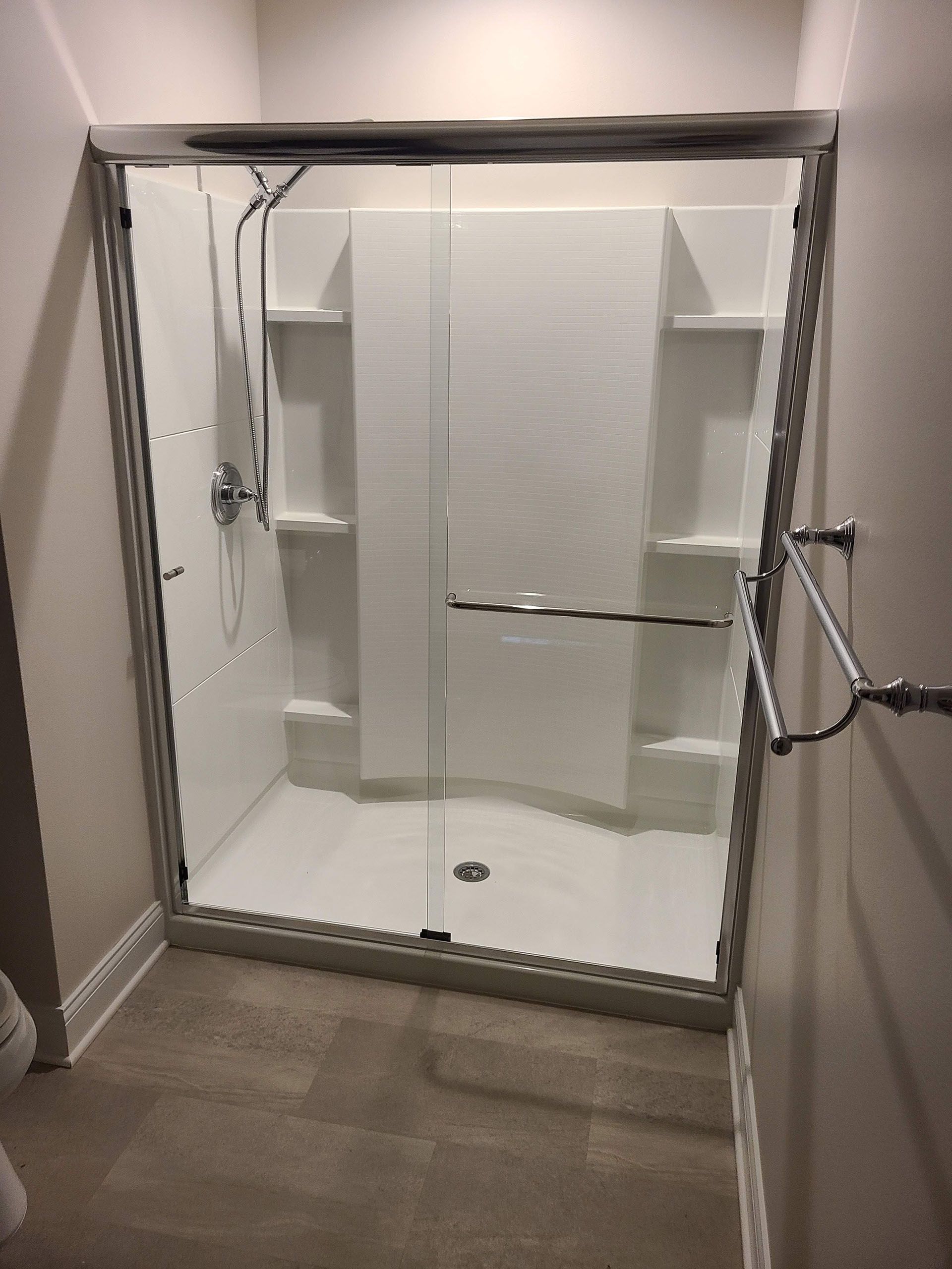 Sliding glass - A bathroom with a sliding glass shower door and shelves.