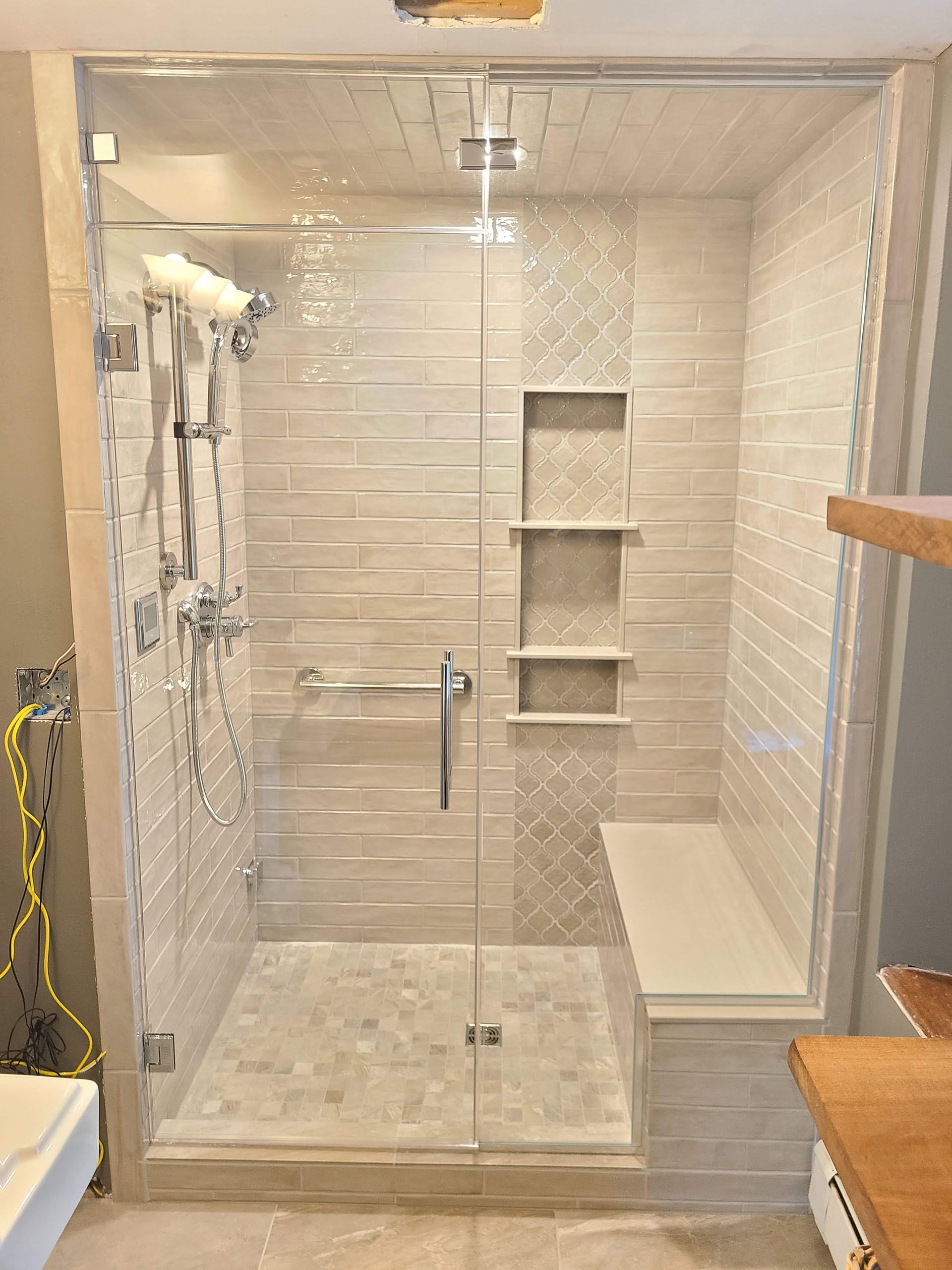 Steam showers - A bathroom with a walk in shower with a glass door and a bench.