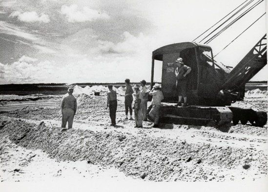 A black and white photo of men standing around a crane