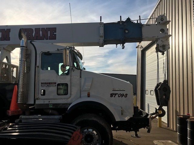 A truck with a crane attached to it is parked in front of a building