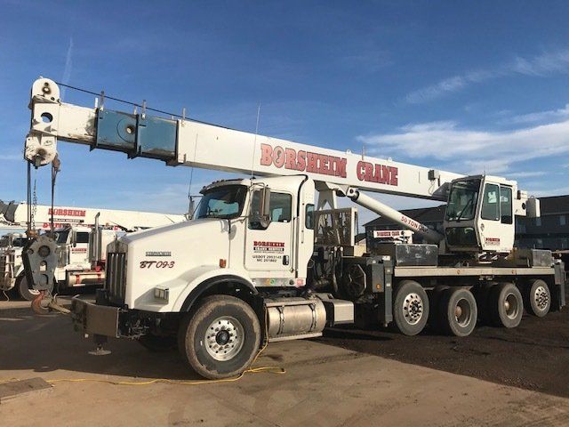A large white truck with a crane attached to it is parked in a parking lot.