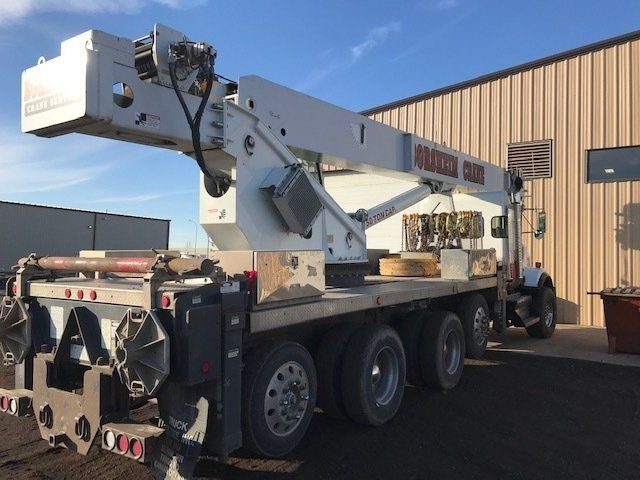 A white crane truck is parked in front of a building