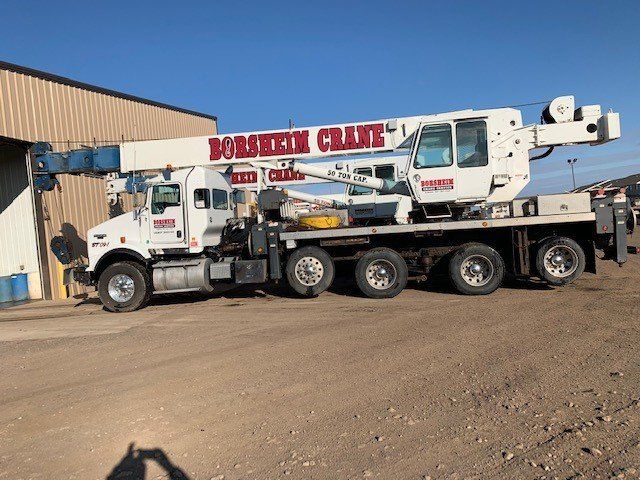 A bobstick crane is parked in front of a building