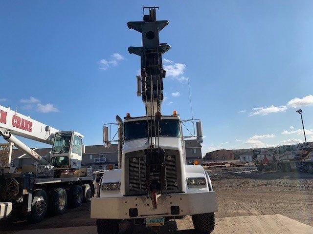 A truck with a crane attached to it is parked in a parking lot.