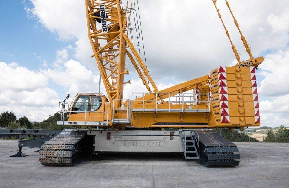 A large yellow liebherr crane is parked in a parking lot