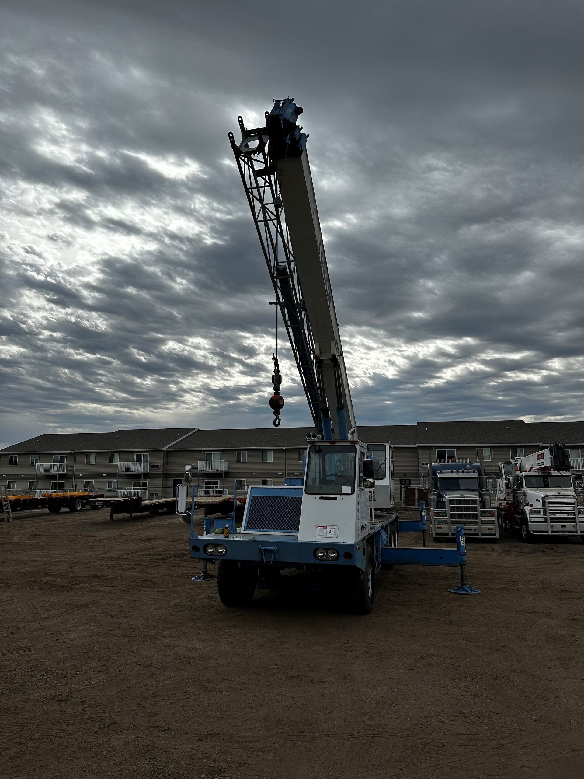 A large crane is parked in a gravel lot