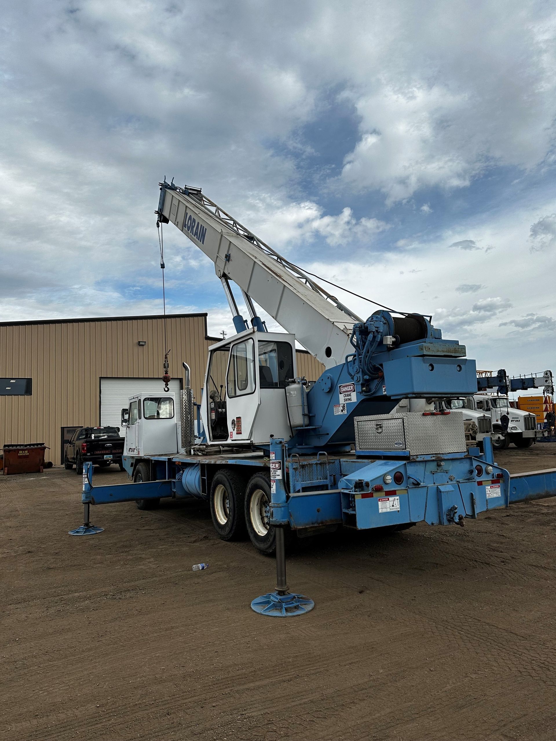A blue and white crane is parked in front of a building.