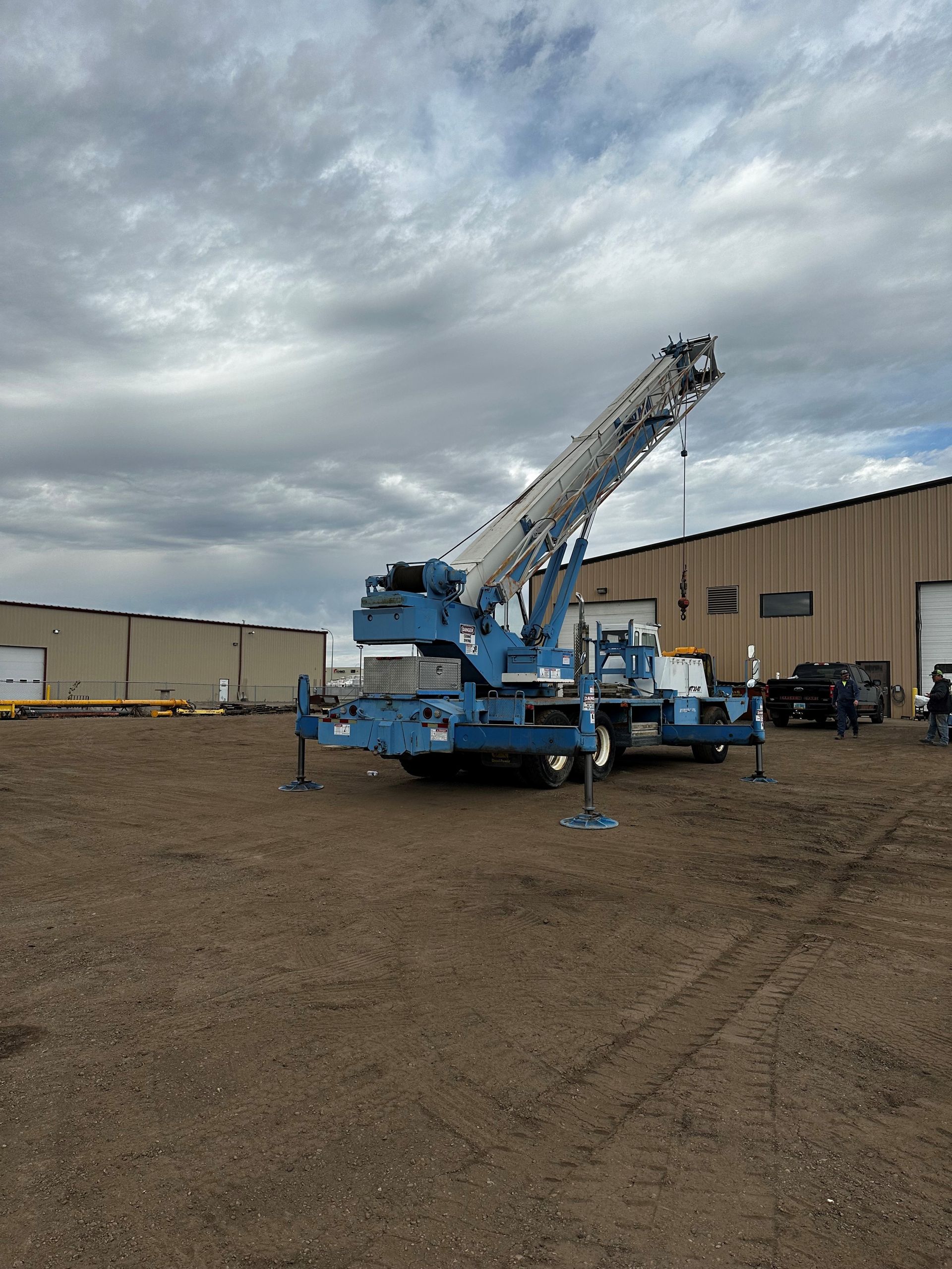 A blue crane is parked in front of a building
