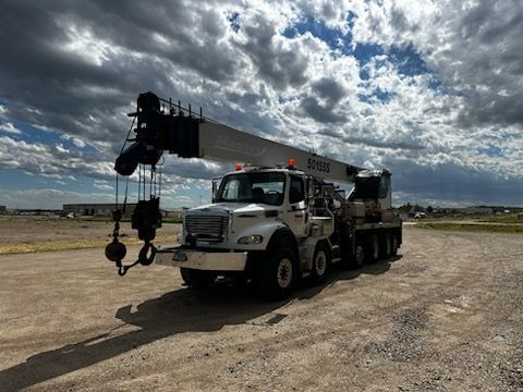 A large crane is parked on the side of a dirt road.