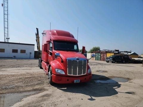 A red semi truck is parked in a dirt lot.