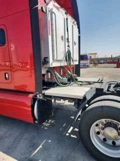A red semi truck is parked in a parking lot.