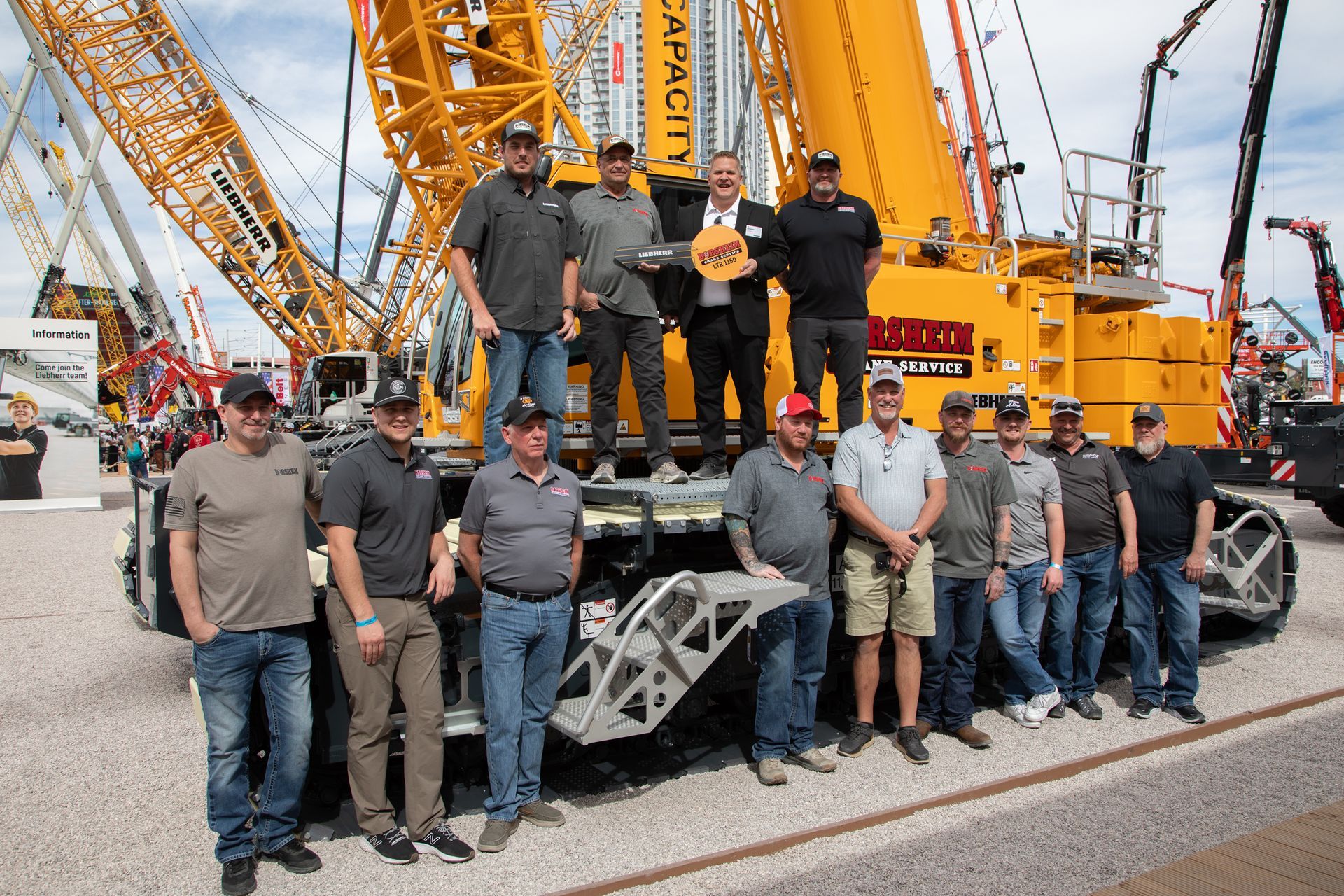 Group of people posing beside a large crane at an industrial site