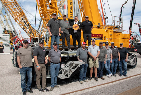large group photo of men standing on or in front of a crane