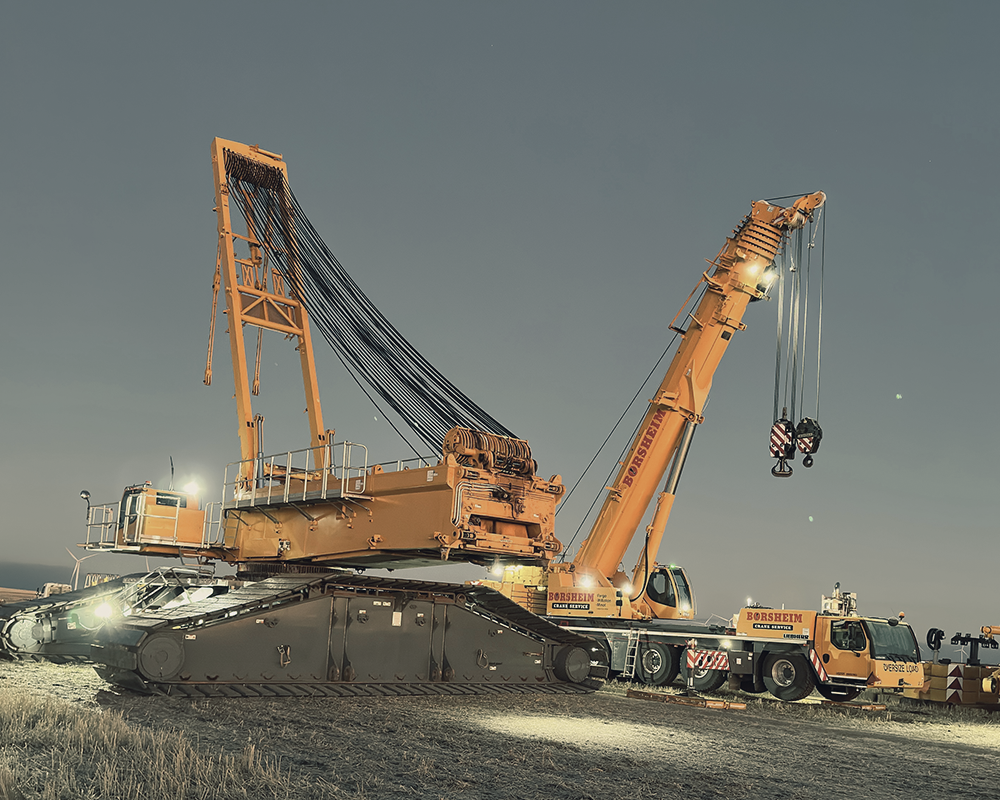 A large orange crane is parked in a field at night.