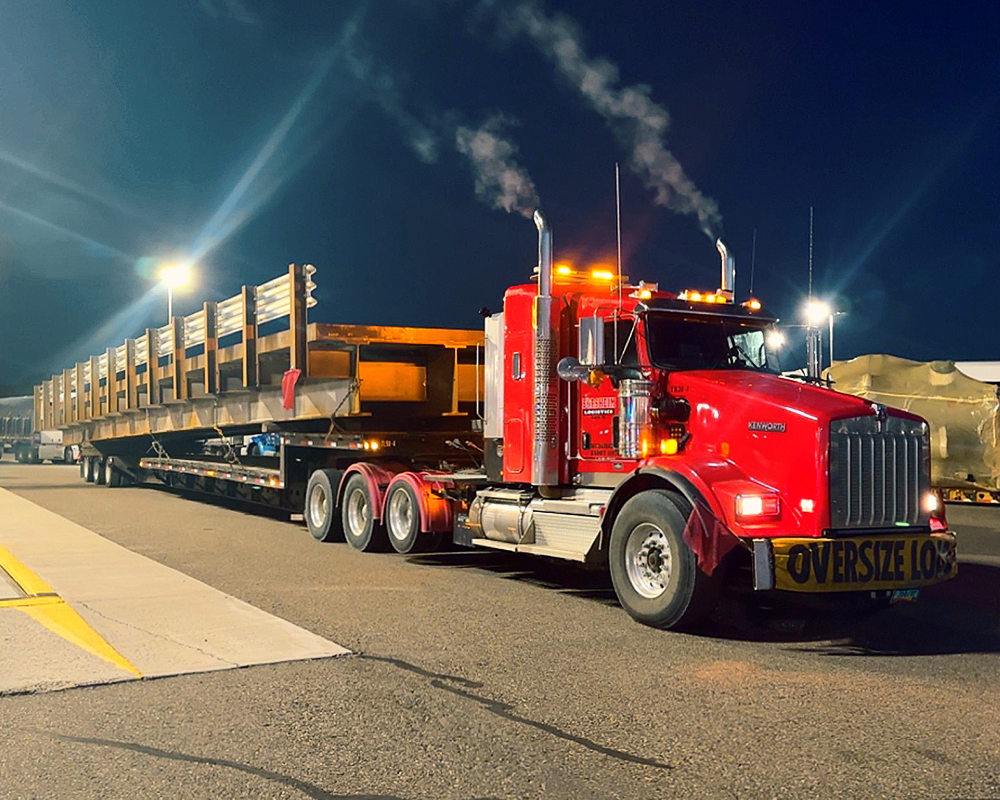 A red semi truck with a yellow sign that says oversize load