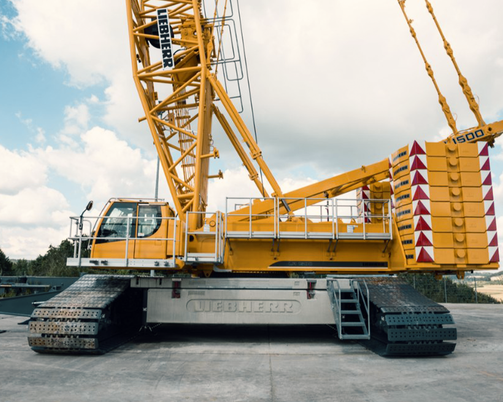 A large yellow liebherr crane is parked in a parking lot