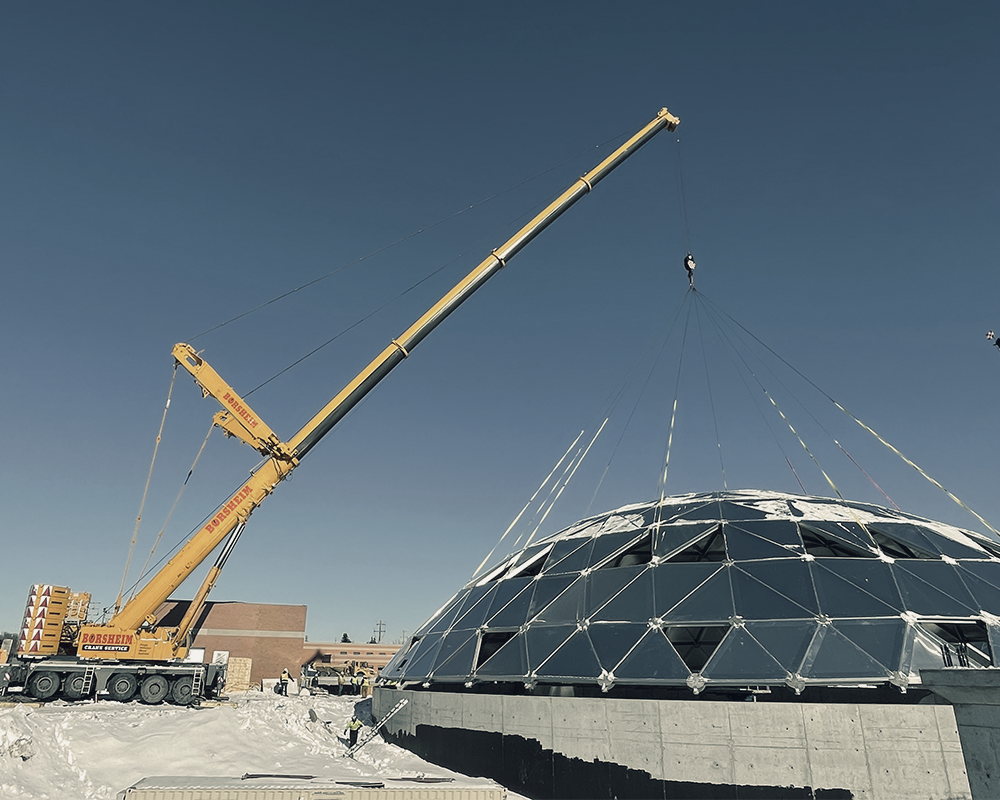 A large yellow crane is working on a dome