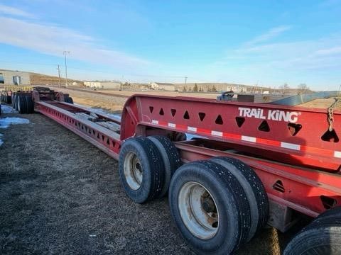A red trail king trailer is parked in a field.
