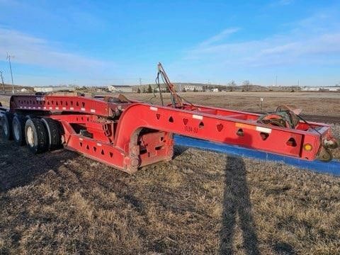 A red trailer is parked in the middle of a field.