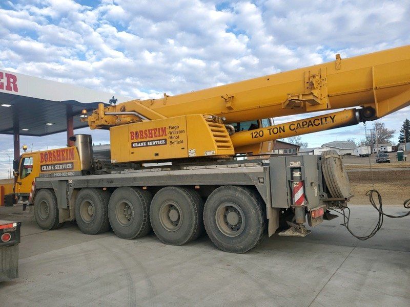 A large yellow crane is parked in front of a gas station.
