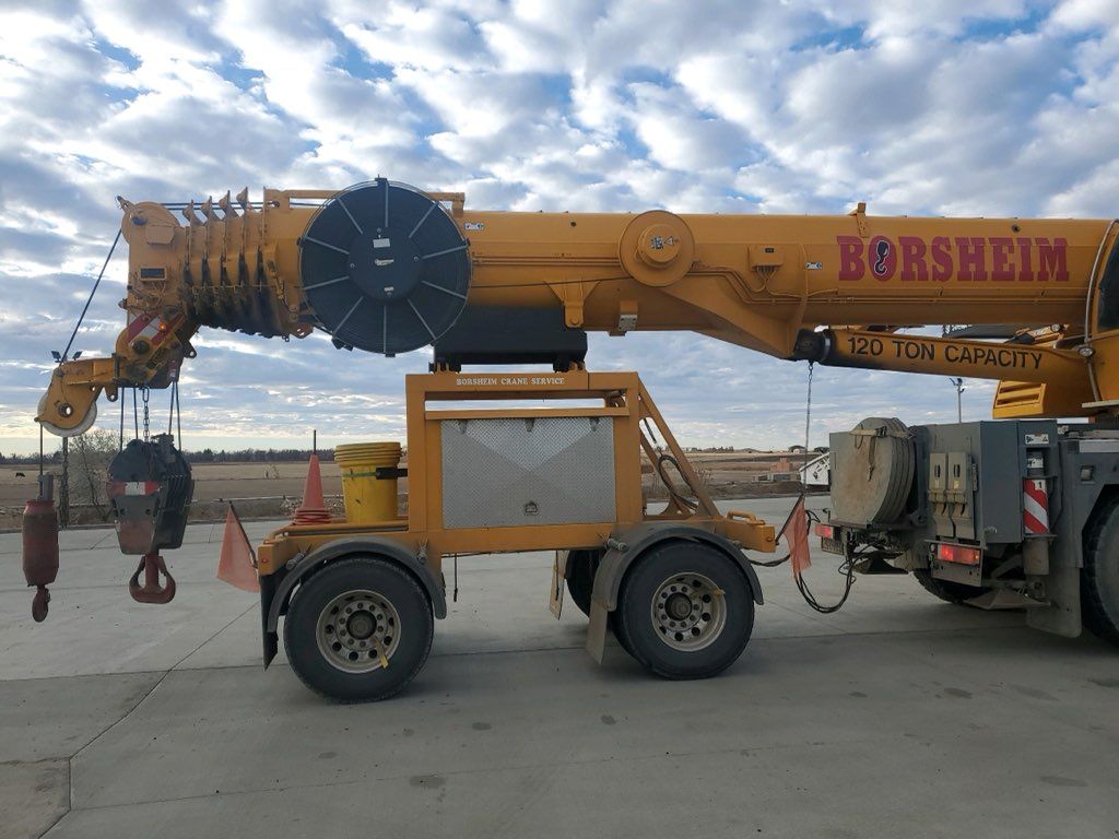 A large yellow borsheim crane is parked on the side of the road