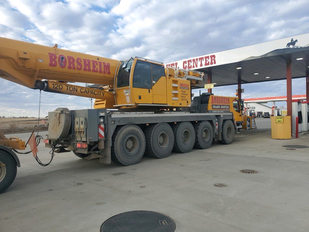 A large yellow crane is parked in front of a gas station.