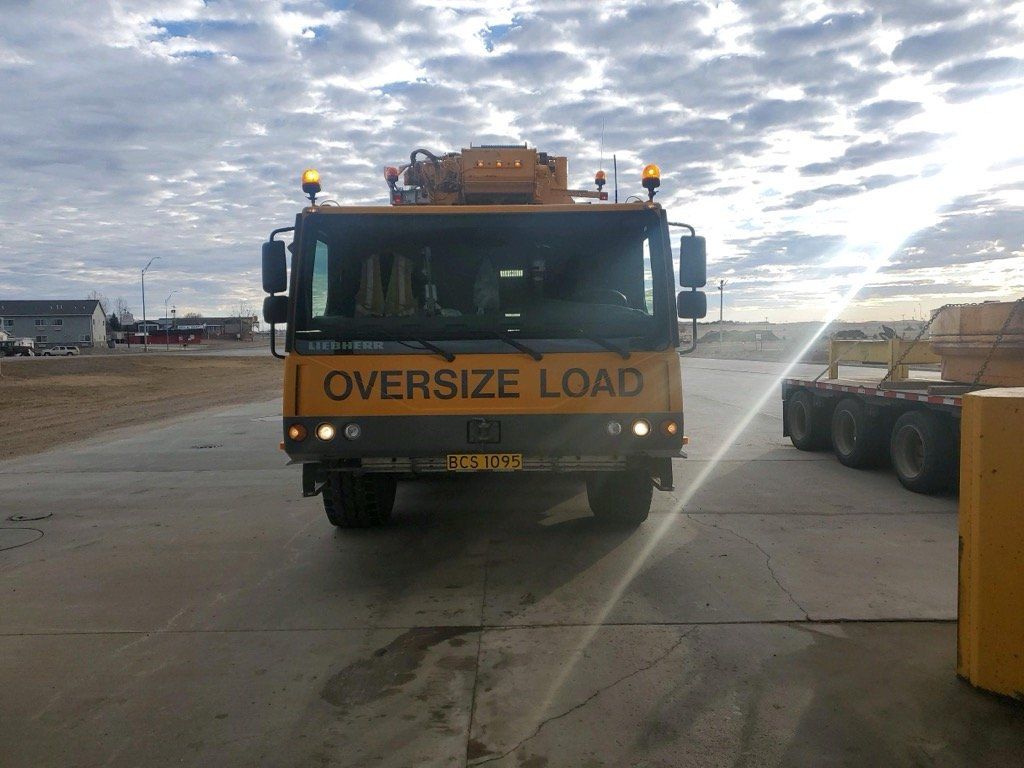 A yellow oversize load truck is parked in a parking lot.