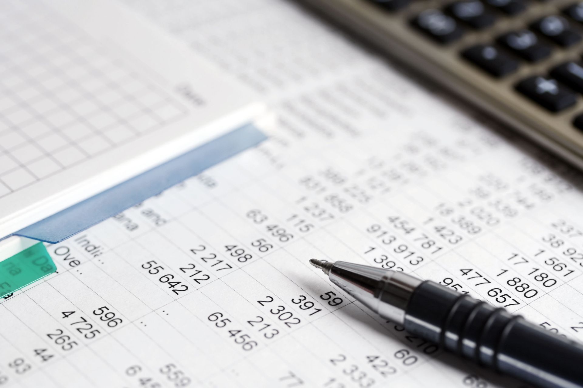 Spreadsheet with numbers, a pen, and a calculator, suggesting financial analysis.