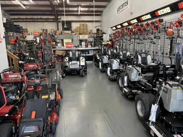 Indoor showroom filled with rows of new commercial mowers and Echo brand string trimmers hanging on the wall. 