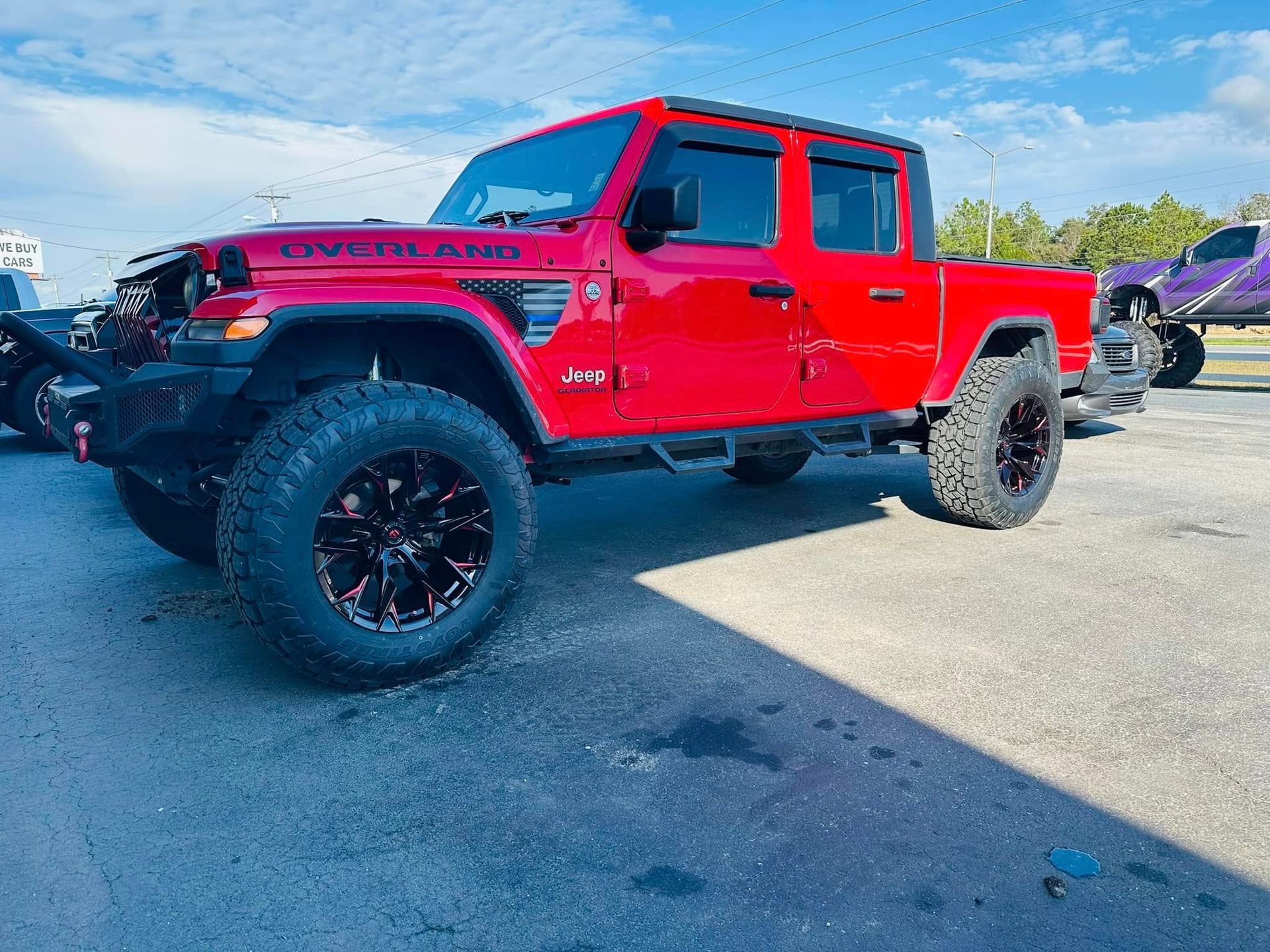 A red jeep is parked in a parking lot.