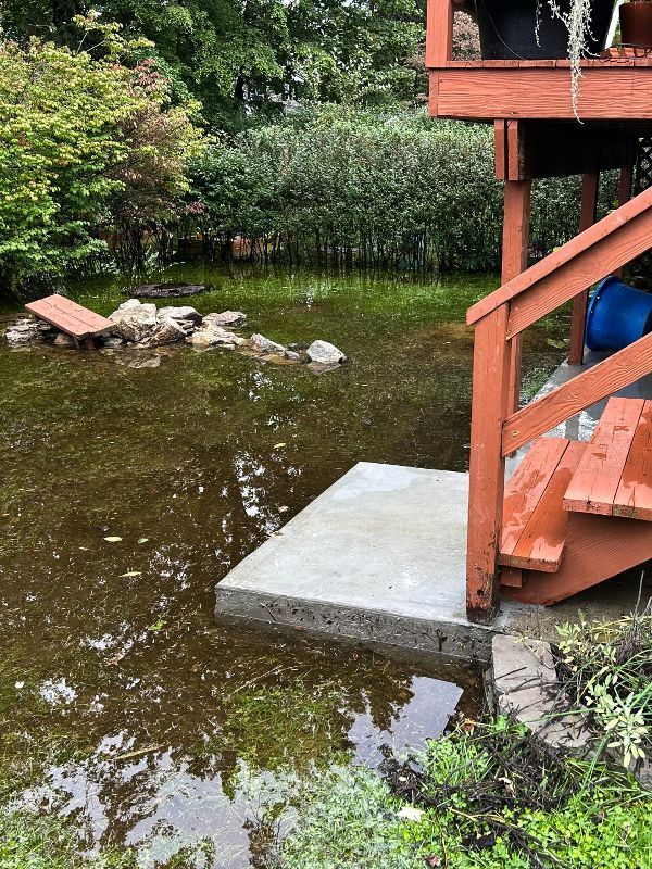 A deck with stairs leading up to a pond filled with water.