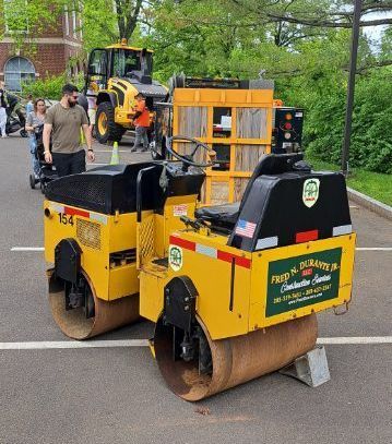 Two yellow asphalt rollers are parked next to each other in a parking lot.