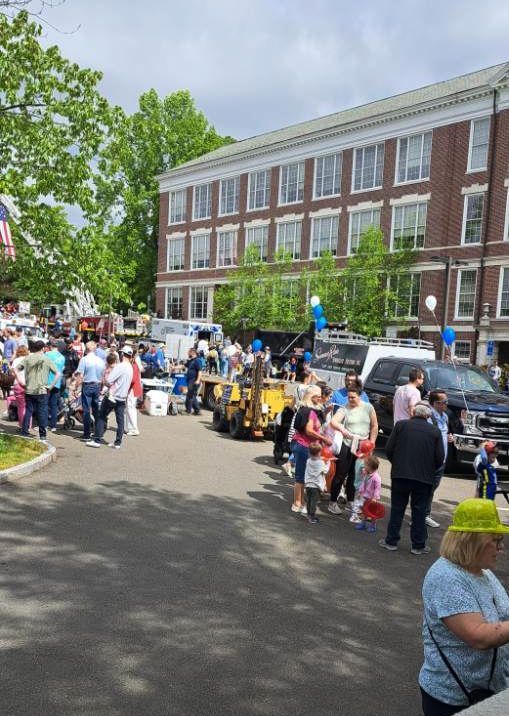 A crowd of people are gathered in front of a large brick building