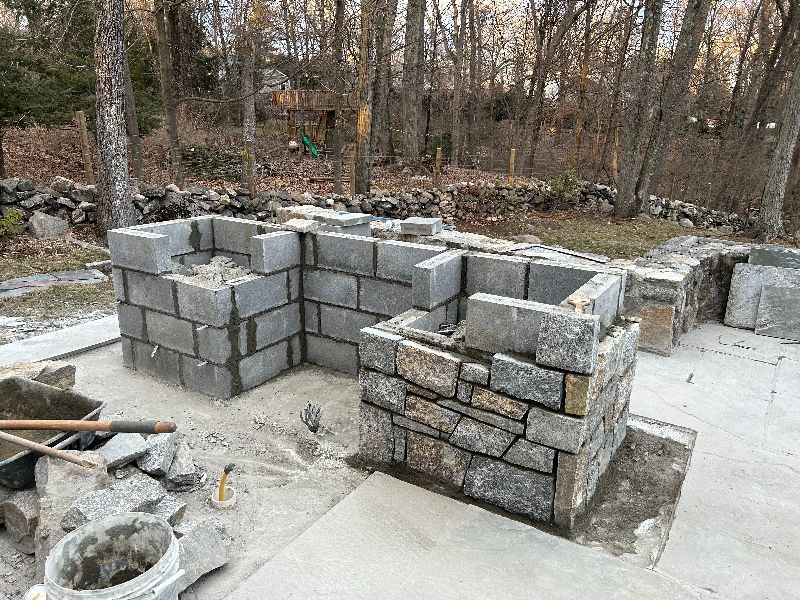 A stone wall is being built in a backyard.