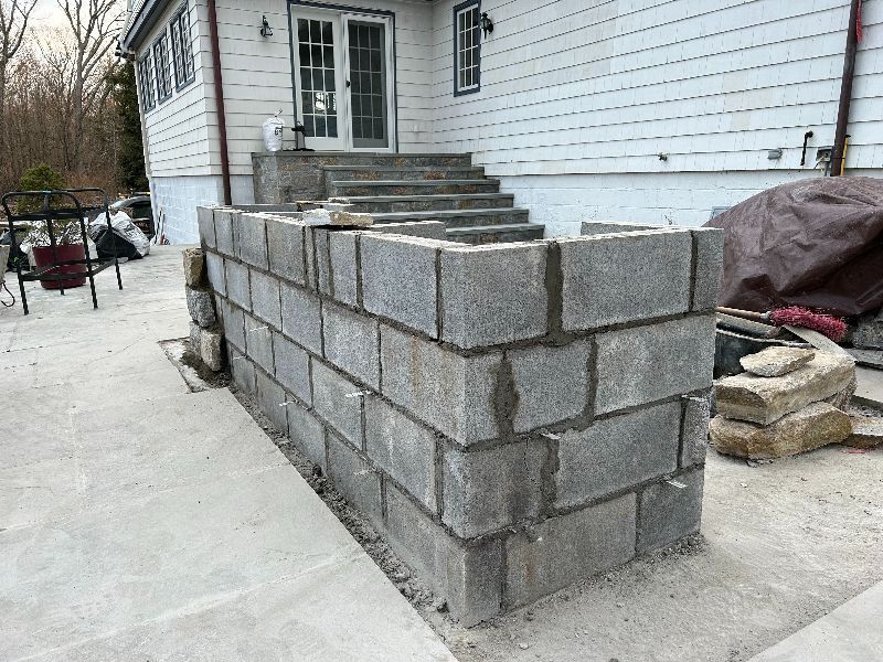 A brick wall is being built in front of a house.