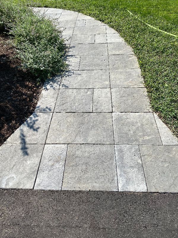 A stone walkway leads to a lush green lawn.
