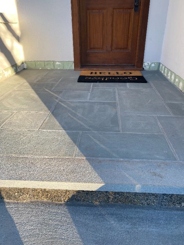 A front porch with a welcome mat and a door.