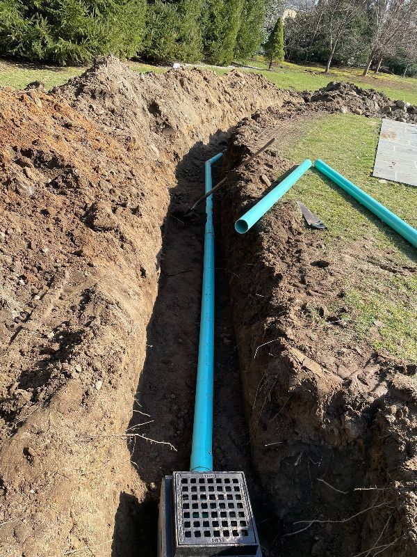 A blue pipe is being installed in a trench.