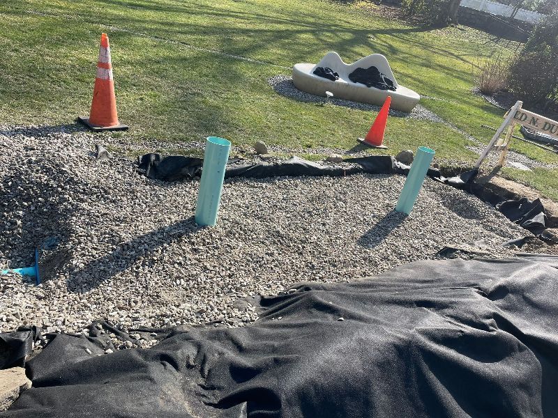 A bunch of pipes are sitting on top of a pile of gravel in a yard.