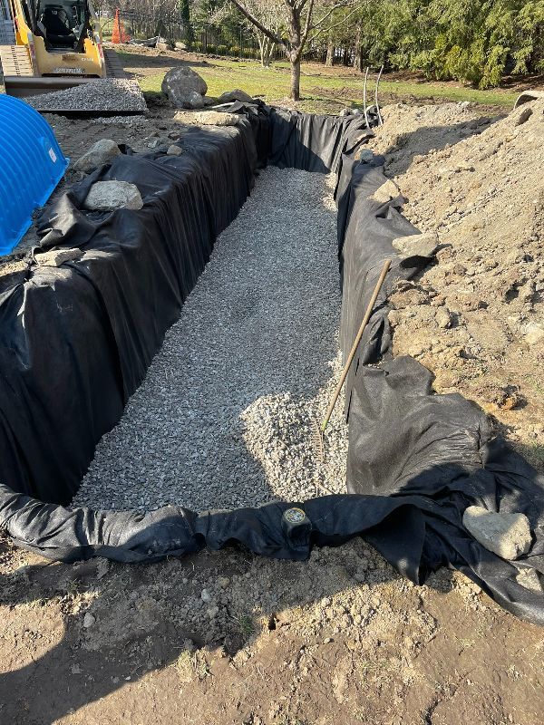 A large pile of gravel is being poured into a trench.