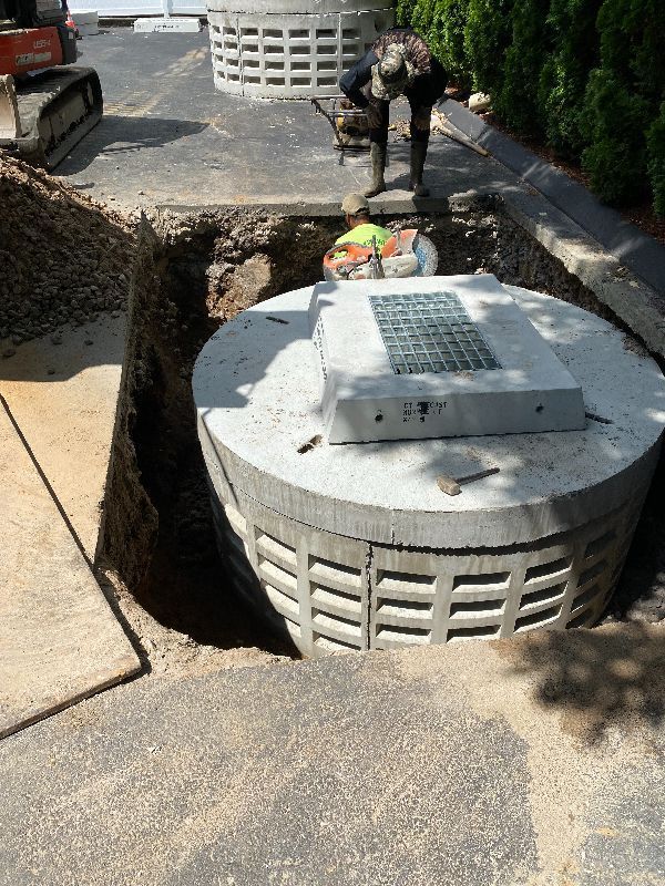 A man is standing in a hole next to a large concrete cylinder.