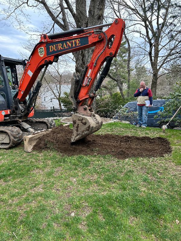 An excavator is digging a hole in the ground in a yard.