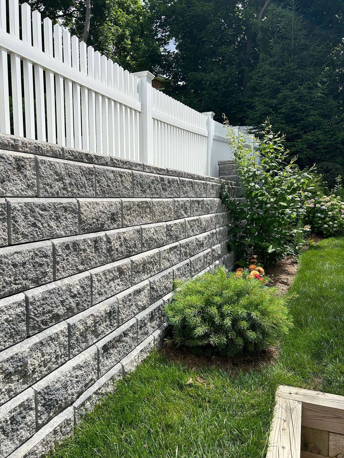 A brick wall with a white picket fence surrounding it.