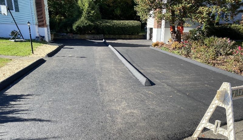 A black asphalt driveway with a white a on the side of it.