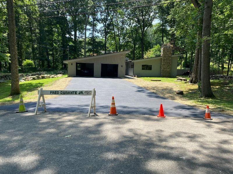 A house with a driveway that has a barrier and cones in front of it.
