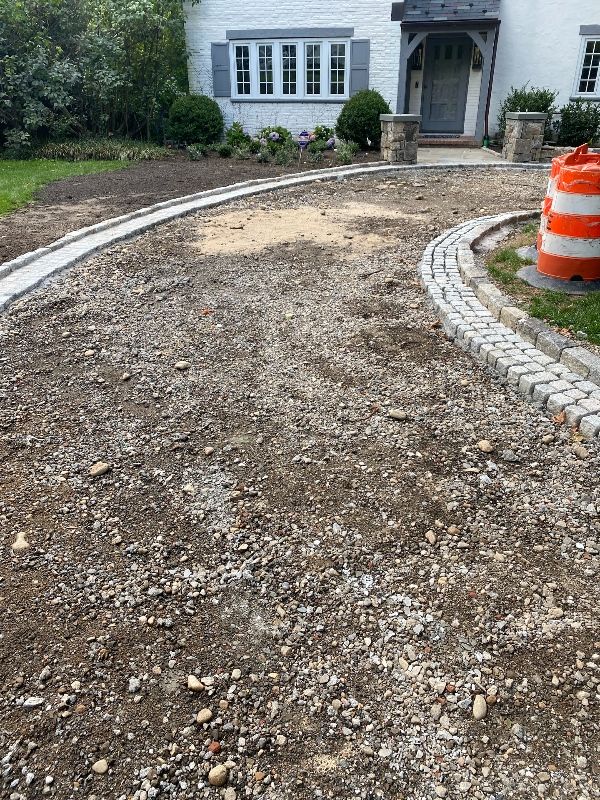A gravel driveway is being built in front of a white house.